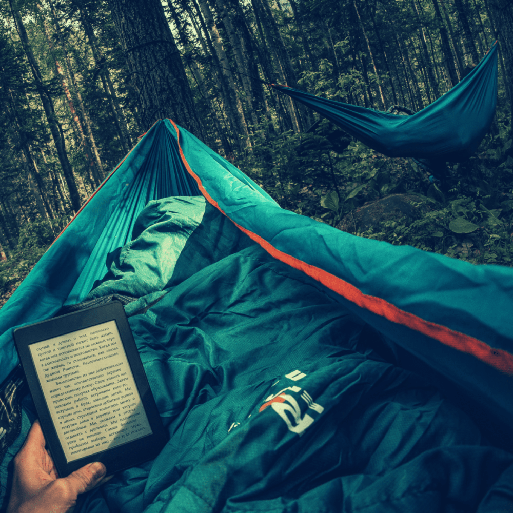 person in hammock reading kindle